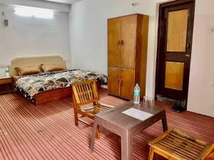 a bedroom with a bed and a table and a chair at OYO Hotel Rohtang View in Manāli