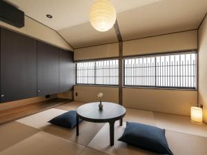 een woonkamer met een tafel en 2 ramen bij Hotori Machiya House in Kanazawa