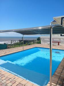 uma piscina azul com um guarda-sol e o oceano em Shotleft on Wye RD em Margate