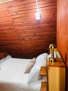 a bedroom with a bed with a wooden wall at Aquawood Cabins in Kianyaga