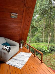 a couch sitting on a porch of a wooden cabin at Aquawood Cabins in Kianyaga