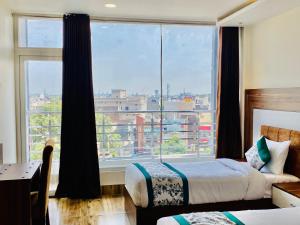 ein Hotelzimmer mit 2 Betten und einem großen Fenster in der Unterkunft Hotel White house near Golden Temple in Amritsar