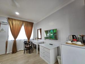 Cette chambre blanche dispose d'un bureau, d'une table et d'une fenêtre. dans l'établissement Cottage Inn Gerik, à Gerik