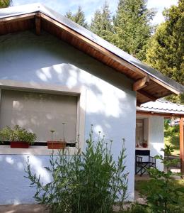 um edifício branco com uma janela com um telhado de madeira em Casa con jardín - Circuito Chico, Bariloche em San Carlos de Bariloche