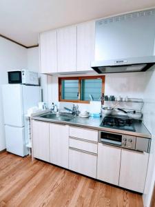 a kitchen with white cabinets and a sink and a refrigerator at Oasis Aoto in Tokyo