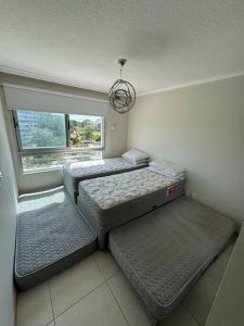 three beds in a room with a window at Ocean drive 2 full amenities in Punta del Este