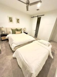 two beds in a room with white sheets at Comfortable Modern Home in Downtown Houston - Sleeps 10 in Houston