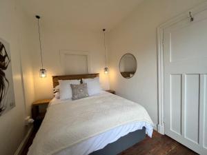 Un dormitorio con una cama con sábanas blancas y un espejo. en Harbour View Villa., en Mossel Bay