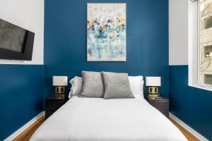 a blue bedroom with a white bed and two lamps at Verdant Statuesque Intimate Acropolis Views Of Famous Park in Atlanta