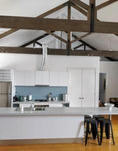 a kitchen with white cabinets and black stools at Pips on Mitchell - Beautiful Historic Apartment in Bendigo