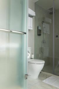 a bathroom with a toilet and a glass shower stall at Airline Inn - Kaohsiung Station in Kaohsiung