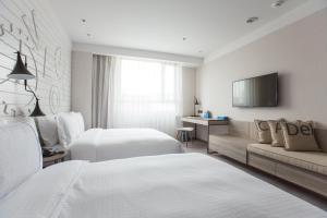 a hotel room with two beds and a couch at Airline Inn - Kaohsiung Station in Kaohsiung