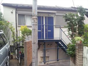 una casa con una puerta azul y una escalera en Maison de Takinogawa, en Tokio