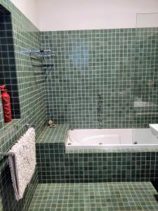 a green tiled bathroom with a tub and a sink at Pips on Mitchell - Beautiful Historic Apartment in Bendigo
