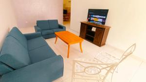 a living room with a couch and a table and a tv at 184 Kulai Homestay Tmn Gunung Pulai 3BR 9pax Shortstay in Kulai
