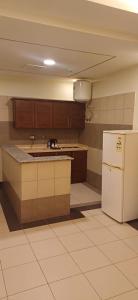 an empty kitchen with a white refrigerator and cabinets at ريف الخرج 2 للشقق الفندقية in Al Kharj