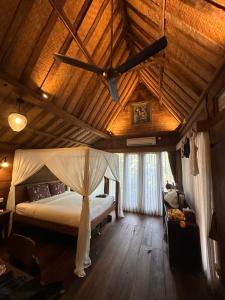 a bedroom with a bed with a ceiling fan at Umakayu Joglo Villa Canggu - Boutique Hotel in Canggu