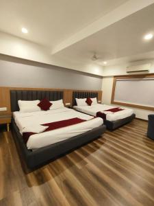 two beds in a hotel room with a projection screen at Hotel welcome somnath in Somnath