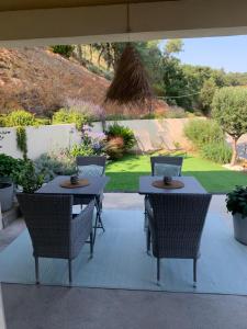 a patio with two tables and chairs and a garden at Suite dans un petit paradis in La Londe-les-Maures