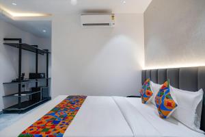 1 dormitorio con 1 cama blanca grande con almohadas coloridas en FabHotel Prime Cloud 5 Studios en Madhapur
