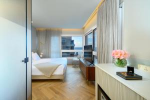 テルアビブにあるJewel TLV Hotelのベッドと大きな窓が備わるホテルルームです。