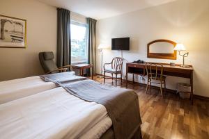 um quarto de hotel com uma cama e uma secretária em First Hotel Bengtsfors em Bengtsfors
