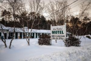 ein Motelschild im Schnee vor einem Gebäude in der Unterkunft West Bethel Motel in Bethel