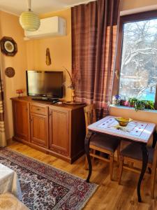 un soggiorno con tavolo e TV a schermo piatto di Cozy apartment with balcony a Sofia