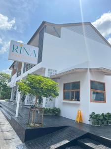 un edificio blanco con un cartel delante en RINA Poolvilla (รินะ พูลวิลล่า) en Hat Yai