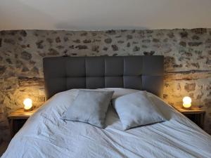 1 cama con 2 almohadas y 2 luces en las mesas en Maison de Vacances L'Etable, en Saint-Just-près-Brioude