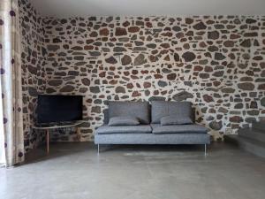 un soggiorno con divano e parete in pietra di Maison de Vacances L'Etable a Saint-Just-près-Brioude