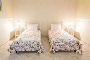 two beds in a room with two tables at Green Hall Hotel in Izmail