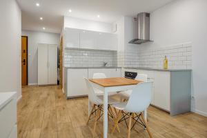 a kitchen with a wooden table and white chairs at Beach&Nature - Bursztynowa in Gdańsk