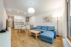 a living room with a blue couch and a table at Beach&Nature - Bursztynowa in Gdańsk