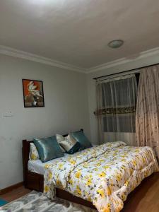 a bedroom with a bed with a yellow and white comforter at Rose house in Dar es Salaam