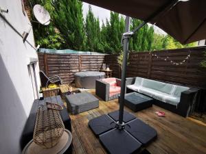 een patio met een parasol en een bank bij Loft Paris Beach + extérieur #Jacuzzi #Barbecue in Fontenay-sous-Bois