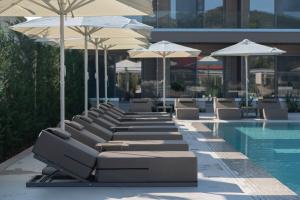 a row of lounge chairs and umbrellas next to a swimming pool at Oniro Boutique Hotel in Toroni