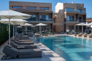 a hotel swimming pool with lounge chairs and umbrellas at Oniro Boutique Hotel in Toroni