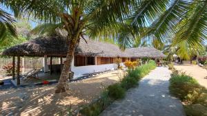 a building with a palm tree in front of it at Ravo Ravo Resort Nosy Be in Antafondro