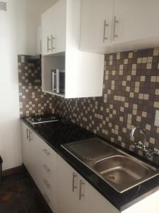 a kitchen with white cabinets and a sink at 24 Onvrey Guest House in Boksburg