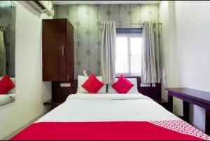 a bedroom with a bed with red pillows and a window at Hotel M in Vijayawāda