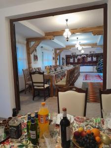 a dining room with a table with fruits and bottles on it at Pensiunea Malinul in Bîrsana