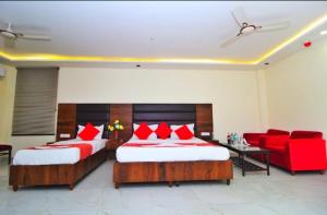 Habitación de hotel con 2 camas y sofá rojo en HOTEL HANUWANT AIRPORT 7 Minutes Distance From IGI AIRPORT 3 Minutes From Aero City Metro Station Book Now For More Offers en Nueva Delhi