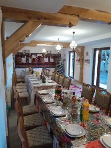 uma sala de jantar com uma mesa longa e cadeiras em Pensiunea Malinul em Bîrsana