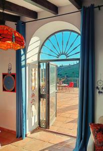 Une porte ouverte s'ouvre sur une terrasse dotée de rideaux bleus. dans l'établissement Beautiful House with Sea View and Nature, 30 minutes from Malaga, à Moclinejo