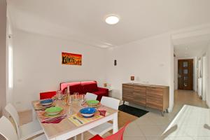 una sala da pranzo con tavolo e divano rosso di La Leonessa - Happy Rentals ad Arco