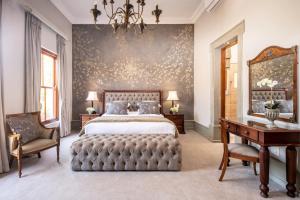 a bedroom with a bed and a table and a chair at Castello Di Monte in Pretoria