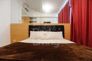Schlafzimmer mit einem Bett mit einem schwarzen Kopfteil und roten Vorhängen in der Unterkunft RedLiving Apartemen TreePark City - Hunian Idamanku Tower Alpine in Kebonnanas + 15 Fotos