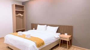 una camera da letto con un grande letto bianco con testiera in legno di ดิ อัยย์ชญา โฮเทล a Ban Phraek Sa