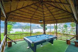 a pool table in a pavilion with a view of the water at DC AROMA VILLA - Venuestay in Hòa Bình